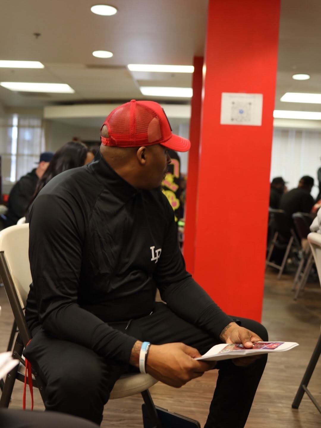 Coach seated at an event holding a program