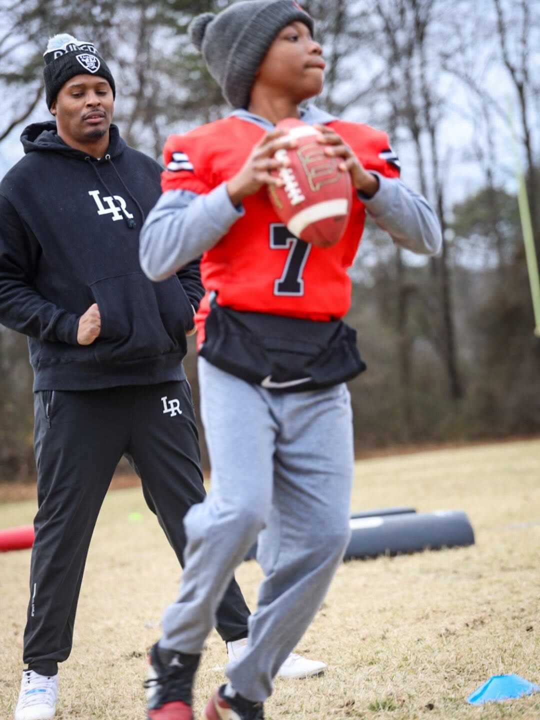 Quarterback training while a coach watches closely